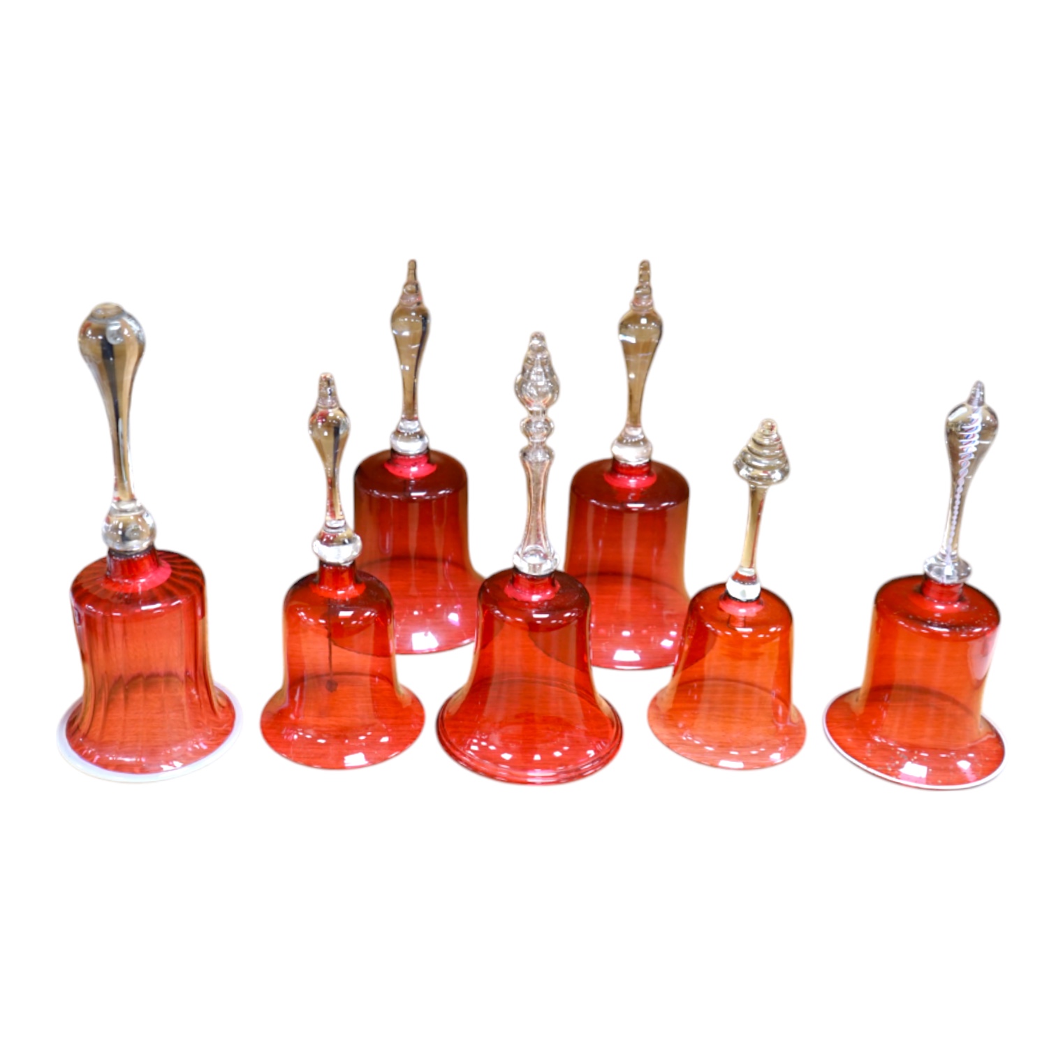 Seven 19th century cranberry glass hand bells, various sizes, largest 30.5cm high. Condition - fair